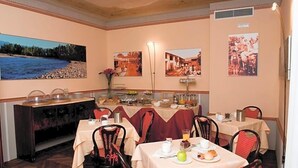 Un comedor con mesas dispuestas para el desayuno, un bufé con diversas opciones de comida, y obras de arte en la pared que representan paisajes y escenas históricas.