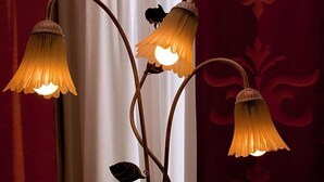 Una lámpara de pared de diseño único, con varias fuentes de luz y un elemento decorativo con forma de hoja.