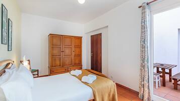 Un dormitorio con cama, armario de madera, puerta y vistas a un patio exterior.