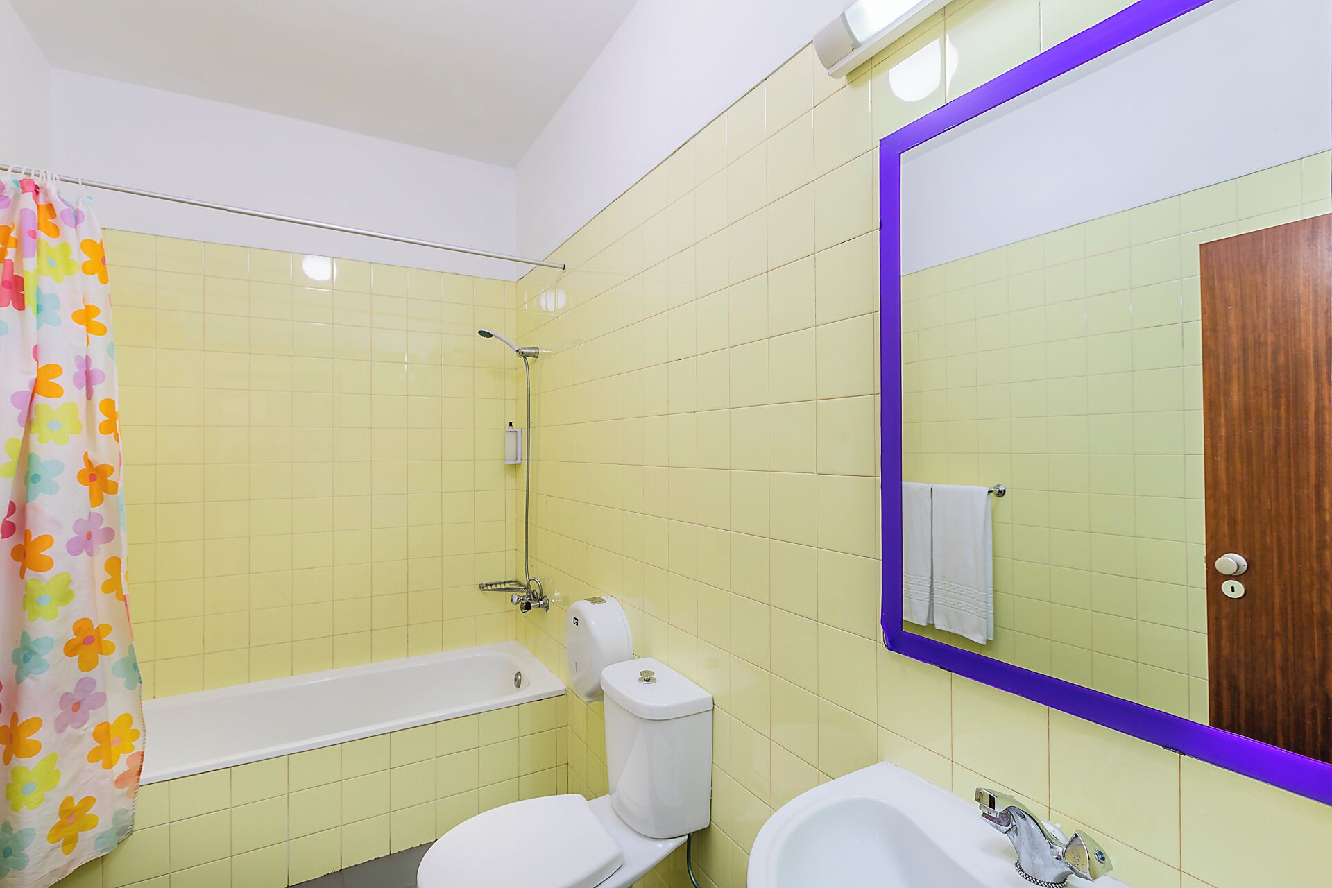 Ein Badezimmer mit gelben Fliesen, einer Dusche, einer Toilette, einer Badewanne und einem Waschbecken.