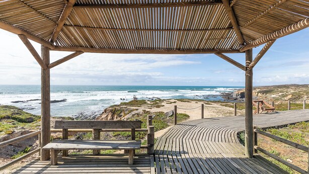 A wooden deck with a bench, a wooden pergola, and a view of the ocean. - HI Almograve - Pousada de Juventude - Hostel (Odemira)