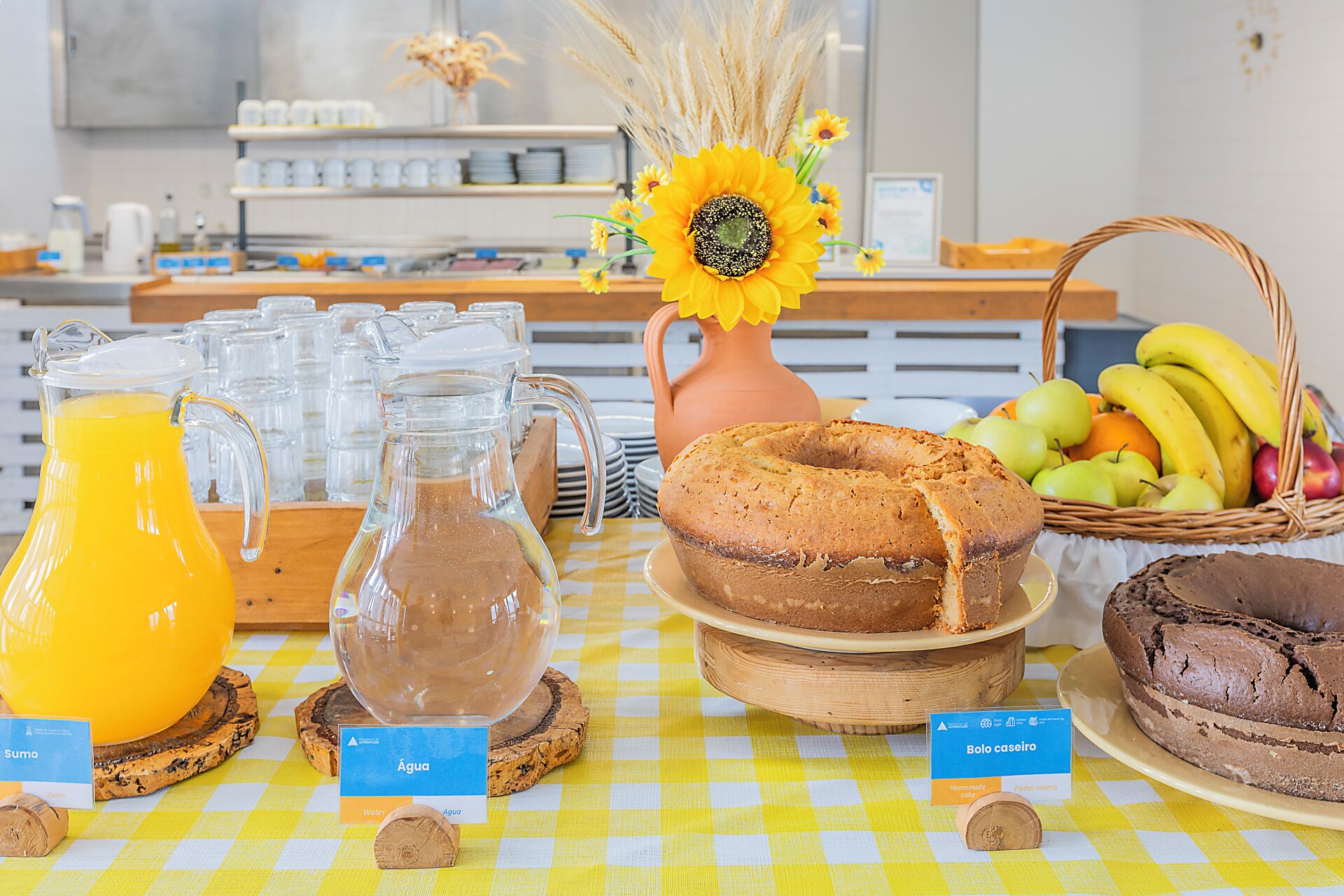 Een ontbijtbuffet met diverse soorten eten, een kan sinaasappelsap en een vaas zonnebloemen.