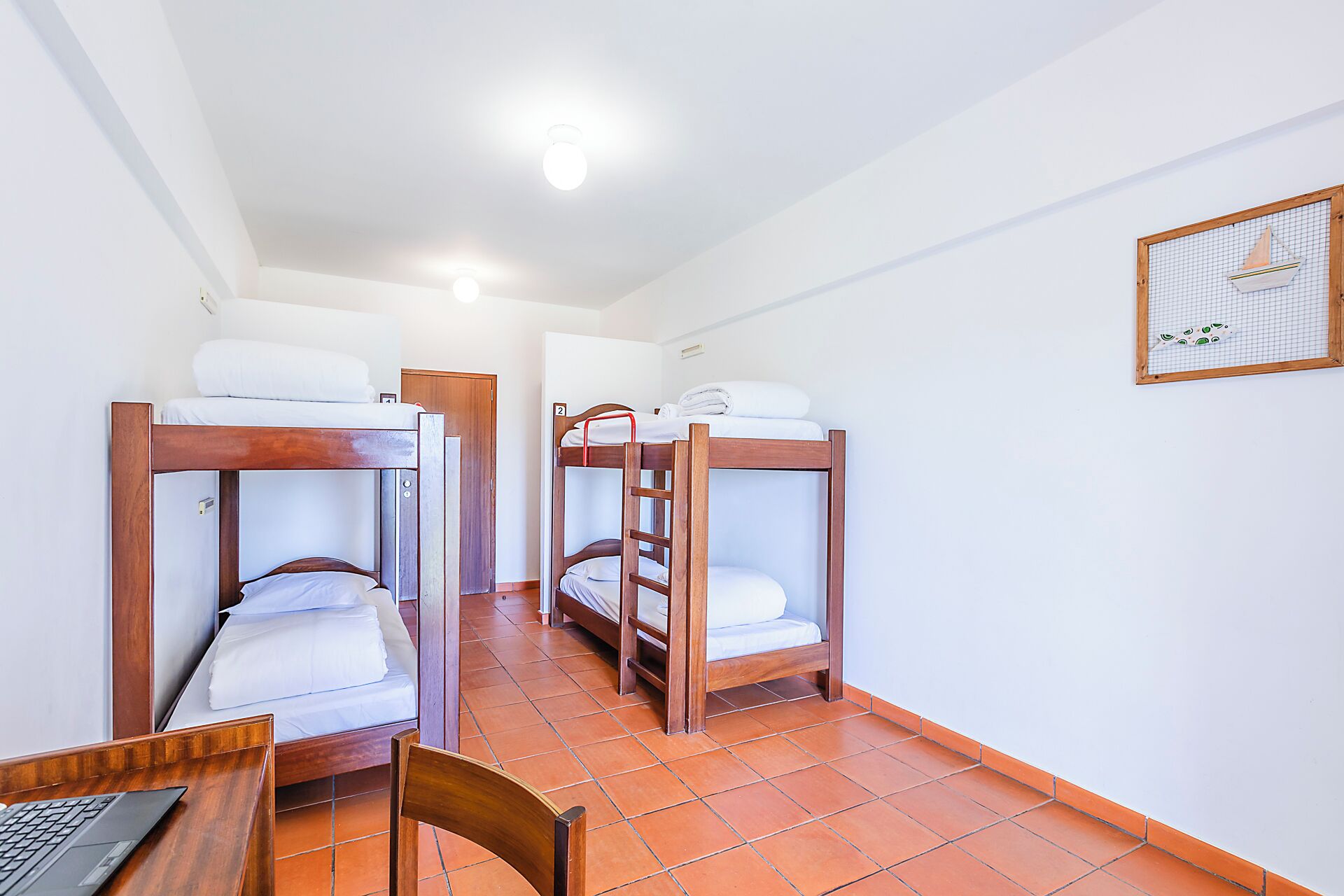 A dormitory room with bunk beds, a desk, and a chair.