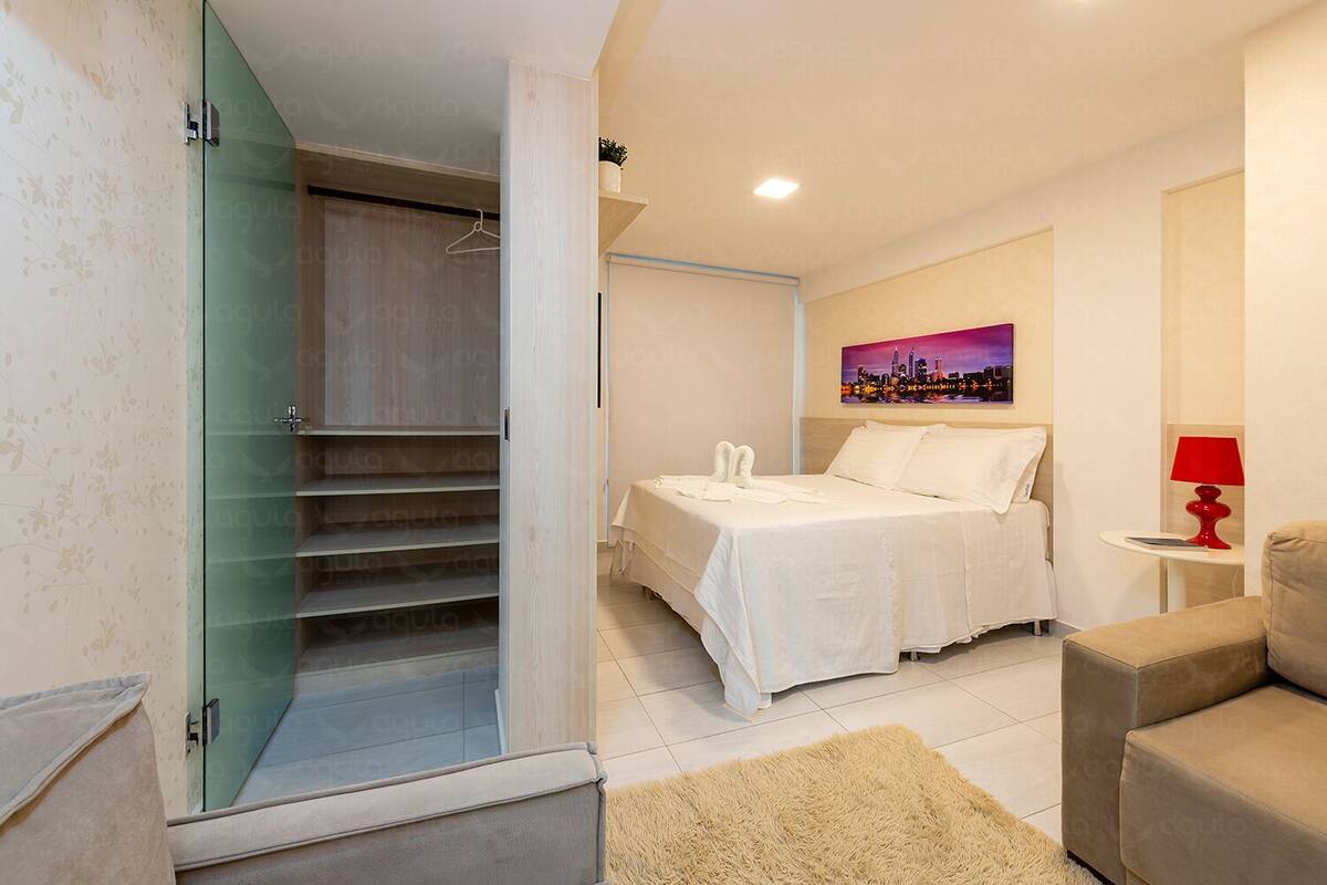 Habitación de hotel con cama, un cuadro de un paisaje urbano, una lámpara roja y un sofá.