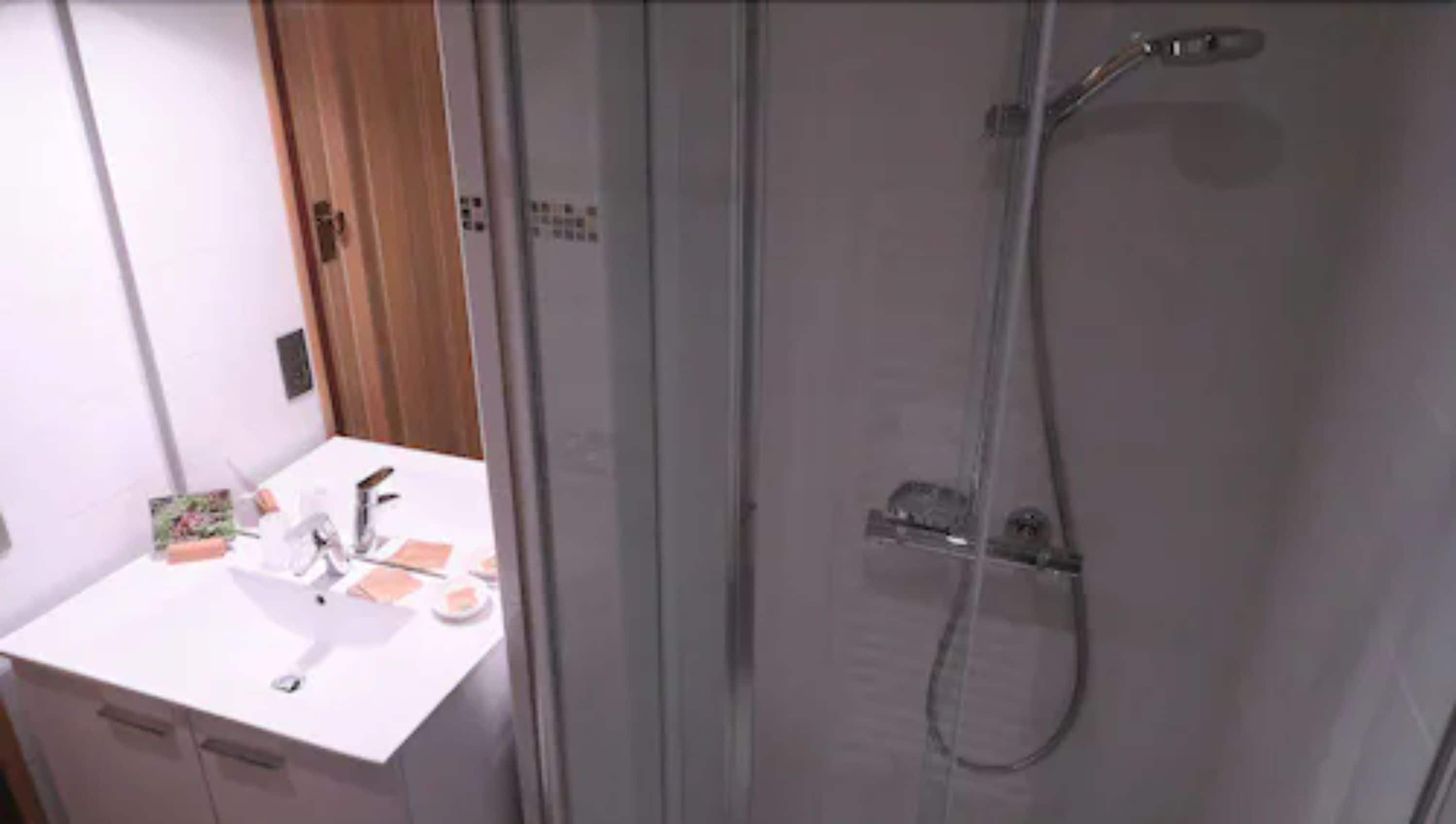 Une salle de bain avec un lavabo blanc, un miroir et une douche à parois de verre.