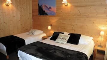 Une chambre avec deux lits, chacun orné d’un coussin à motifs noir et blanc, et un tableau représentant un paysage de montagne accroché au mur.