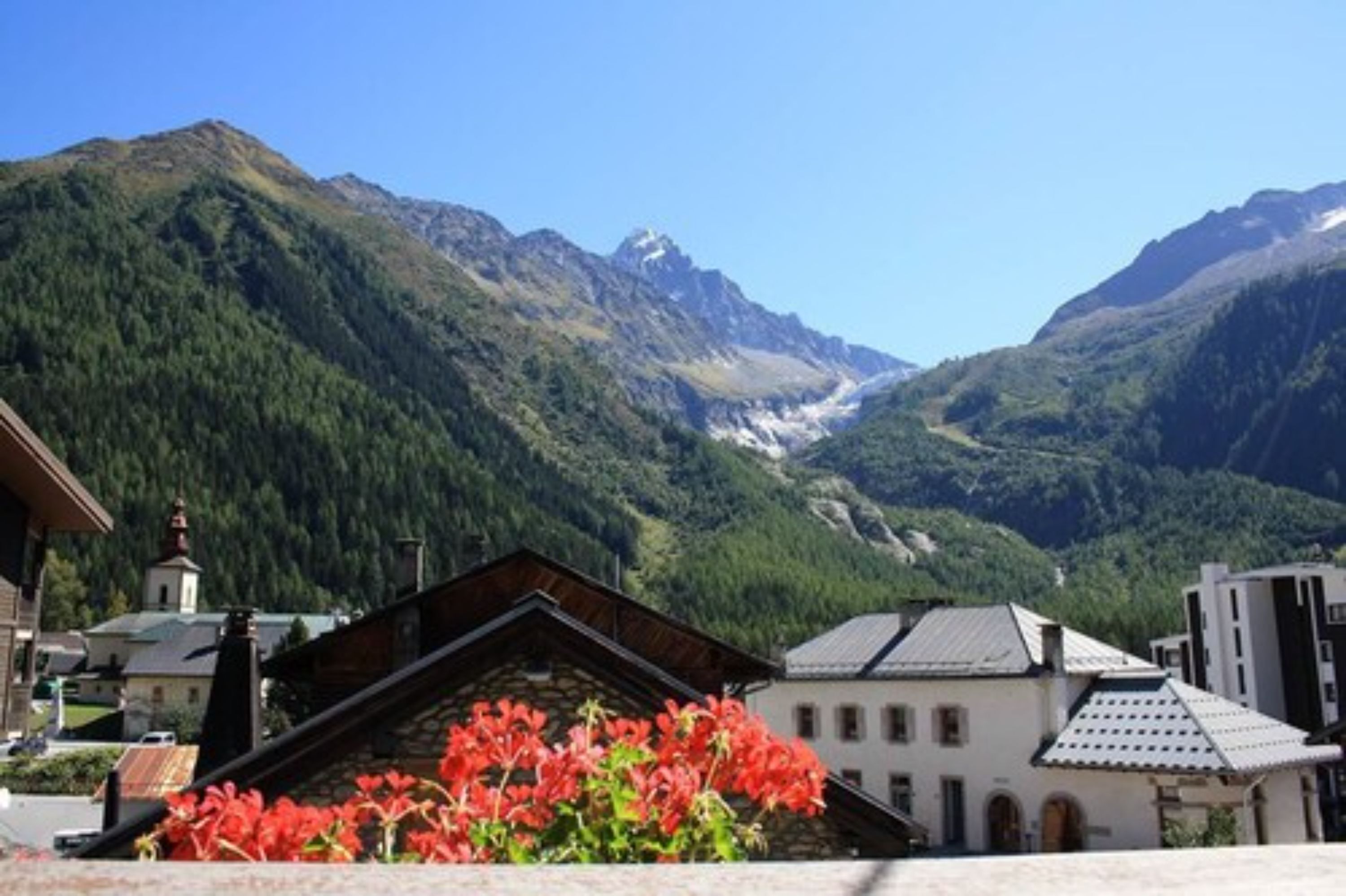 Un villaggio montano con edifici tradizionali, una chiesa e una valle con un ghiacciaio.
