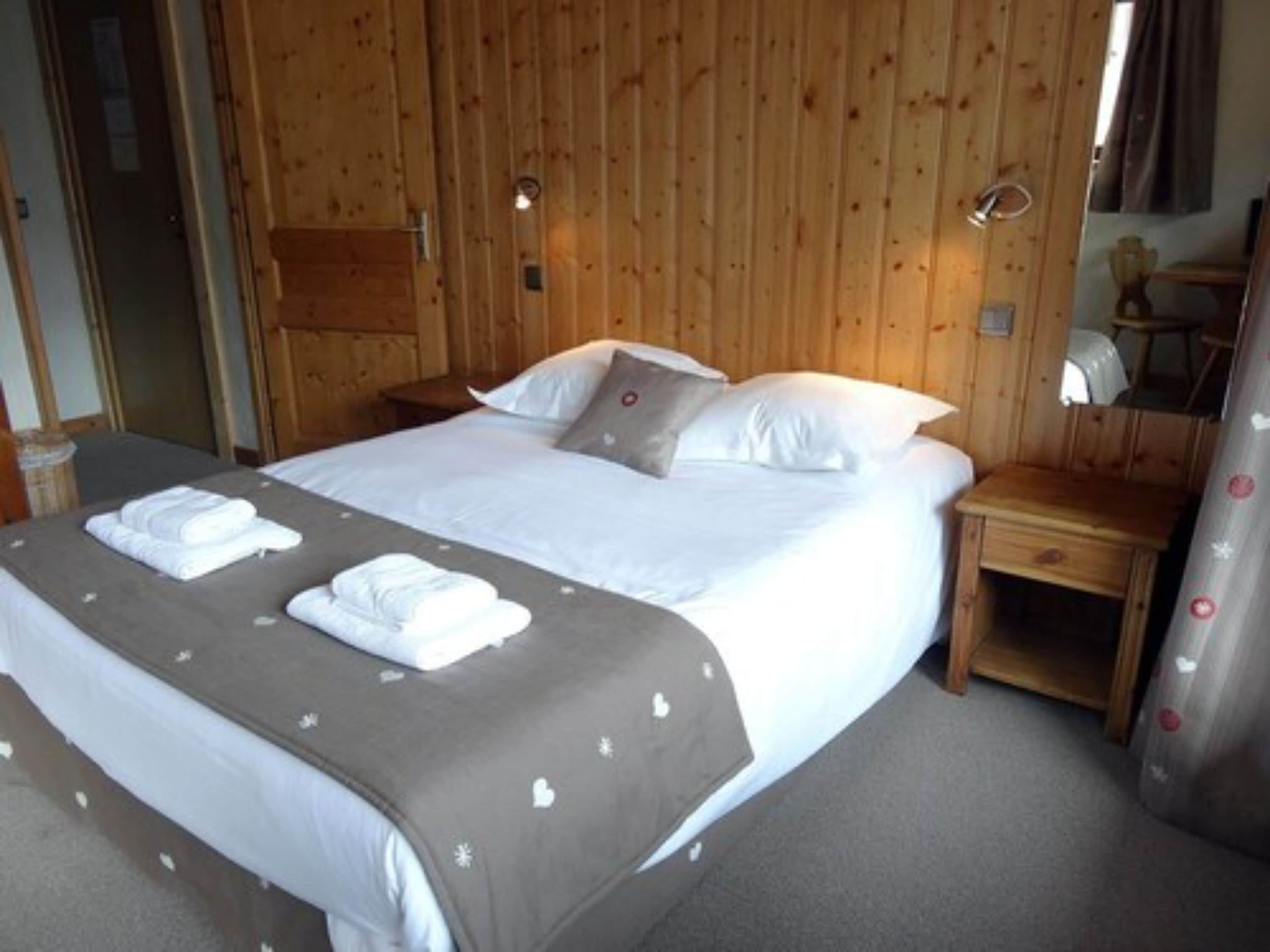 Una habitación con paneles de madera, una cama, una mesita de noche y un espejo.