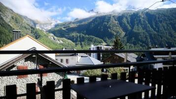 Blick auf eine Berglandschaft mit einem Steinhaus und einem Holzzaun im Vordergrund.