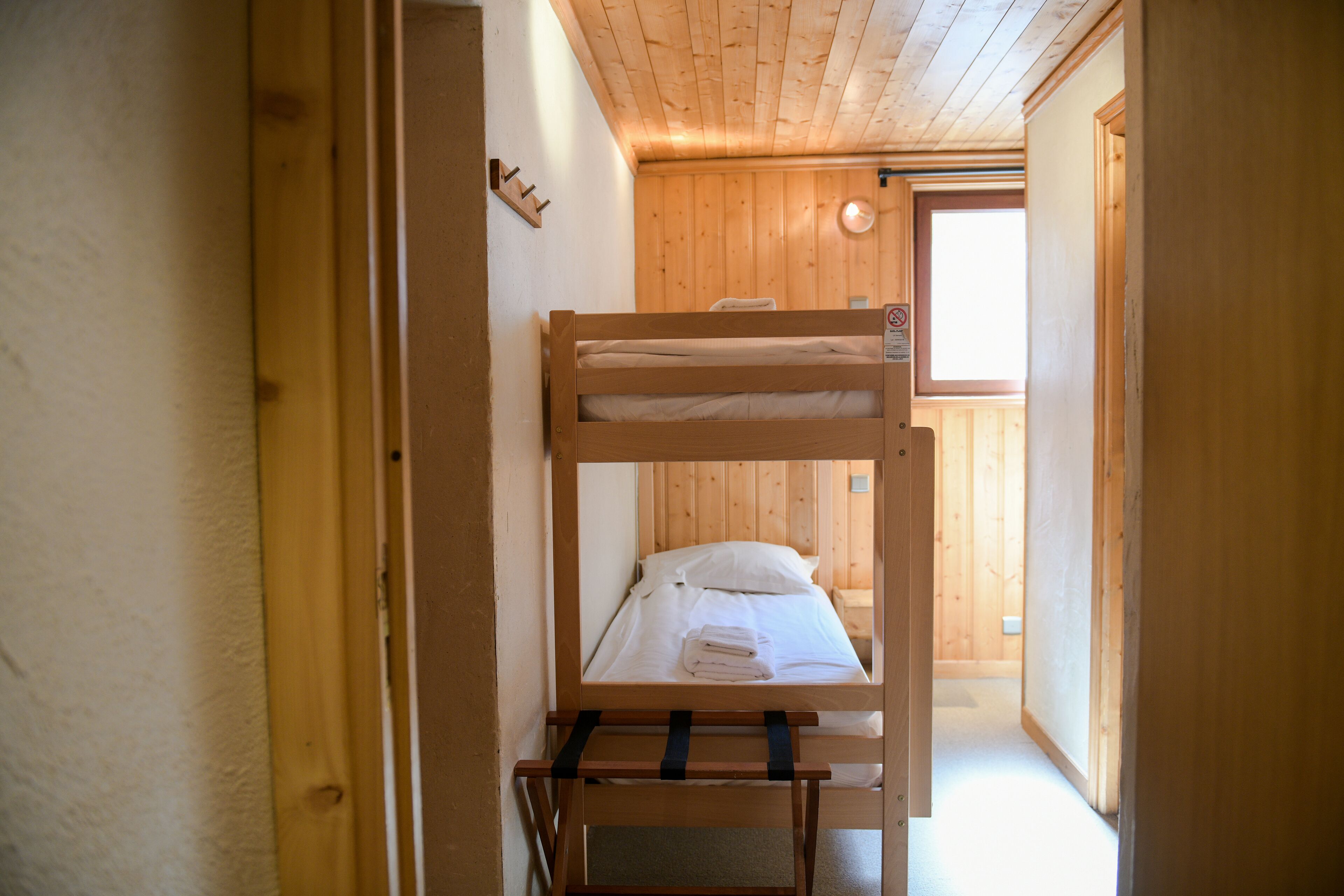 Habitación con literas, paredes de madera y una ventana.