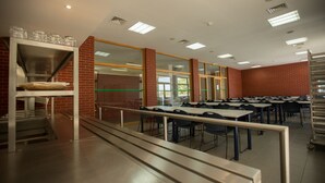 A cafeteria with multiple tables and chairs, a serving counter, and a brick wall. - HI Abrantes - Pousada de Juventude - Hostel (Abrantes)