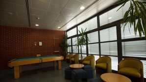 A billiards room with a pool table, yellow chairs, and a potted plant. - HI Abrantes - Pousada de Juventude - Hostel (Abrantes)