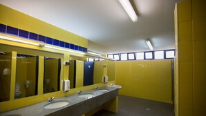 A public restroom with three sinks, a large mirror, and yellow walls. - HI Beja - Pousada de Juventude - Hostel (Beja)