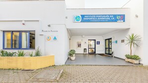 A building entrance with a sign for 'Instituto Português do Desporto e Juventude, I.P.' and a 'Pousada de Juventude' sign. There are potted plants and a paved entrance area. - HI Beja - Pousada de Juventude - Hostel (Beja)