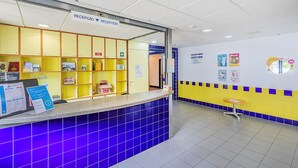 A reception area with a counter, a blue-tiled wall, and a yellow and blue tiled floor. - HI Beja - Pousada de Juventude - Hostel (Beja)