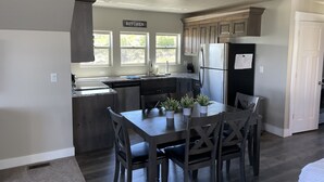 Een moderne keuken met een eethoek, voorzien van een granieten aanrecht, roestvrijstalen apparatuur en een raam met uitzicht op groen.