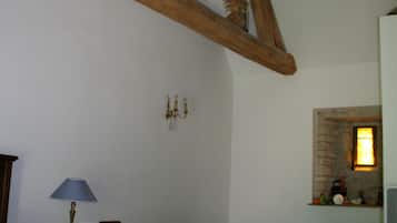 A bedroom with a wooden bed, a nightstand, a lamp, a dresser, and a stone fireplace.