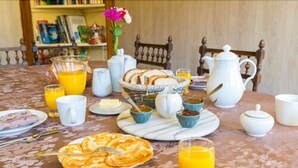 Een ontbijttafel met diverse ontbijtartikelen, zoals pannenkoeken, sinaasappelsap en een karaf sap.