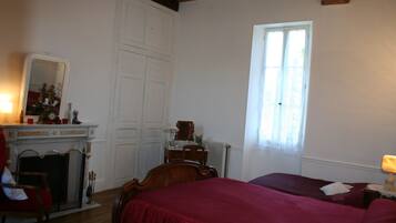 Un dormitorio con cama, cómoda, espejo, chimenea y ventana.