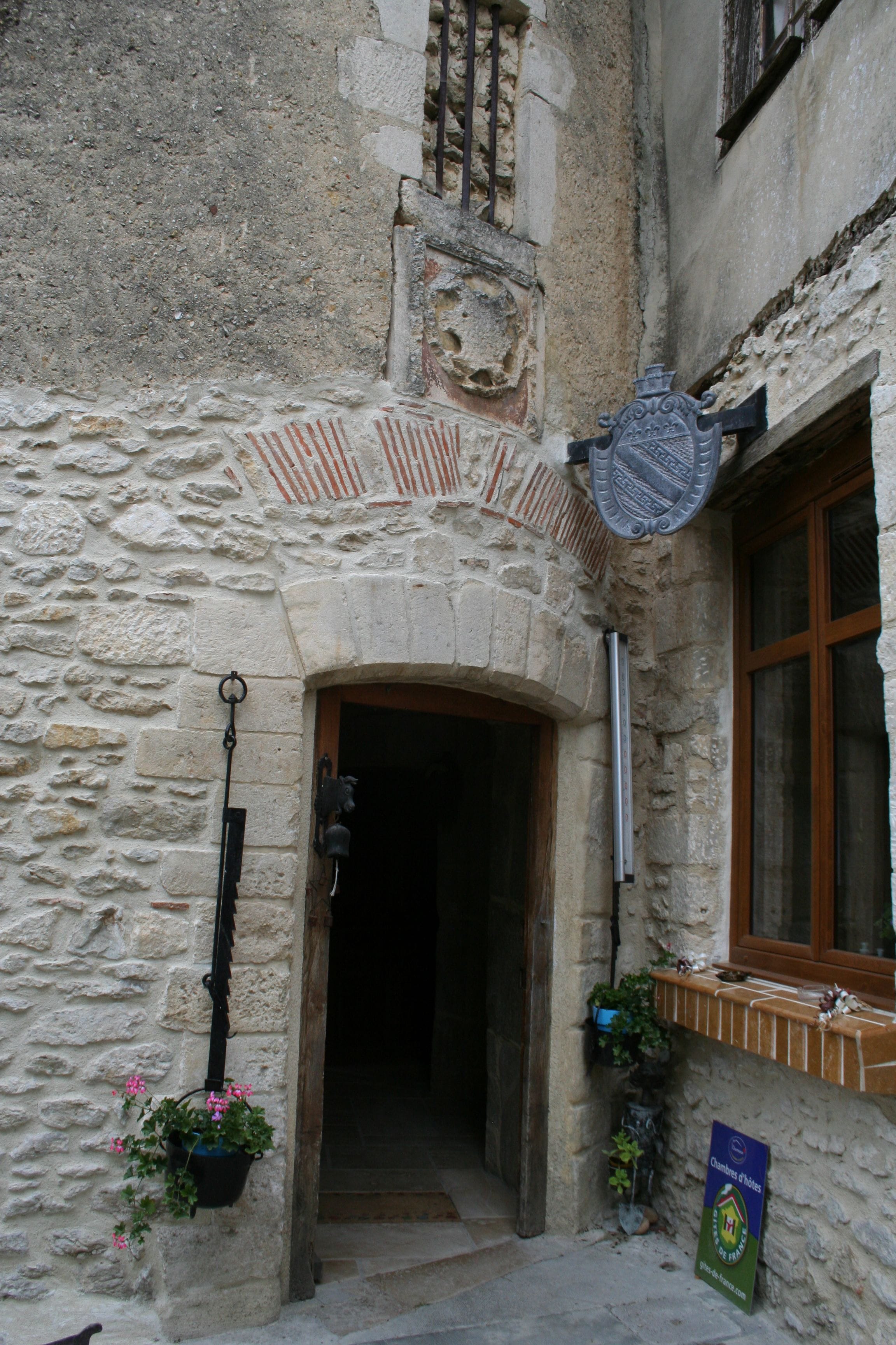 A stone building with a wooden door, a window with a wooden frame, and a sign on the wall.