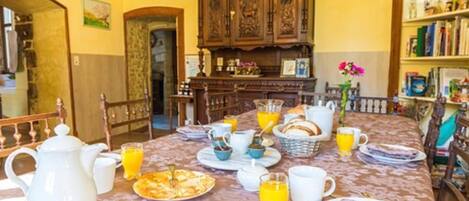 Un comedor con una mesa lista para el desayuno, incluyendo platos, tazas y una jarra.