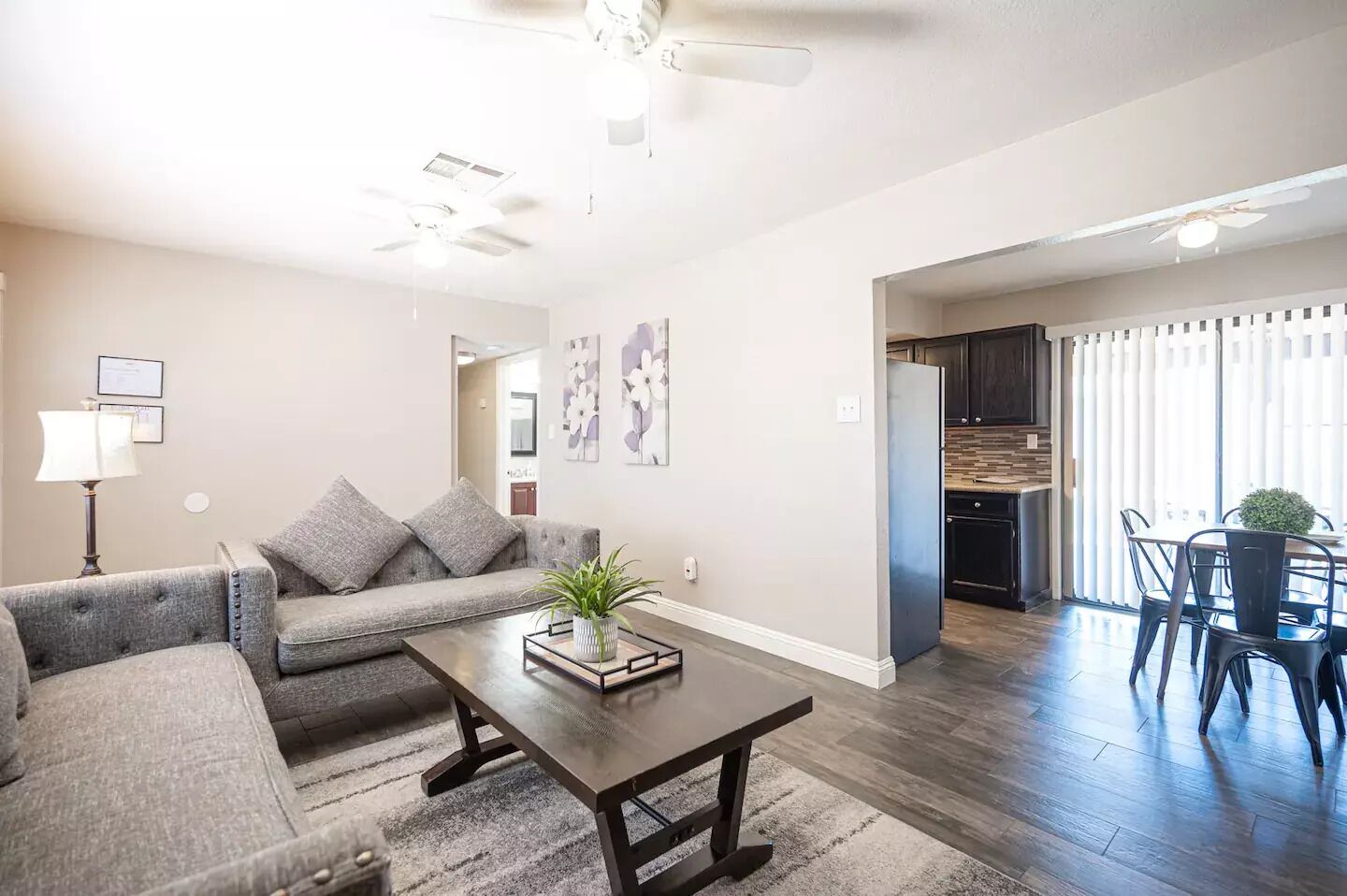 A modern living room with a gray sofa, a coffee table, and a dining area with chairs and a table.
