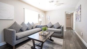 A living room with a grey sofa, a wooden coffee table, and a potted plant.