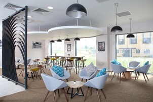 Un interior moderno con una mesa redonda rodeada de sillas, un ventanal con vistas y un techo con iluminación empotrada.