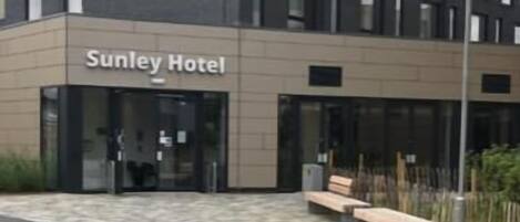 Un edificio moderno con el nombre 'Sunley Hotel' en la fachada.