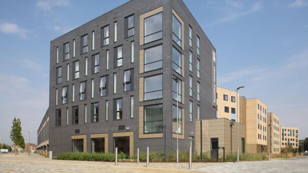 Un immeuble moderne à plusieurs étages, doté d’un toit plat, de grandes fenêtres et d’une façade lisse.
