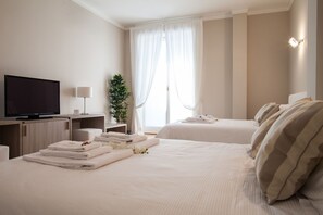 A hotel room with two beds, a TV, a desk with a lamp, and a plant. - Milan Royal Suites Luxury Apartments (MILAN)
