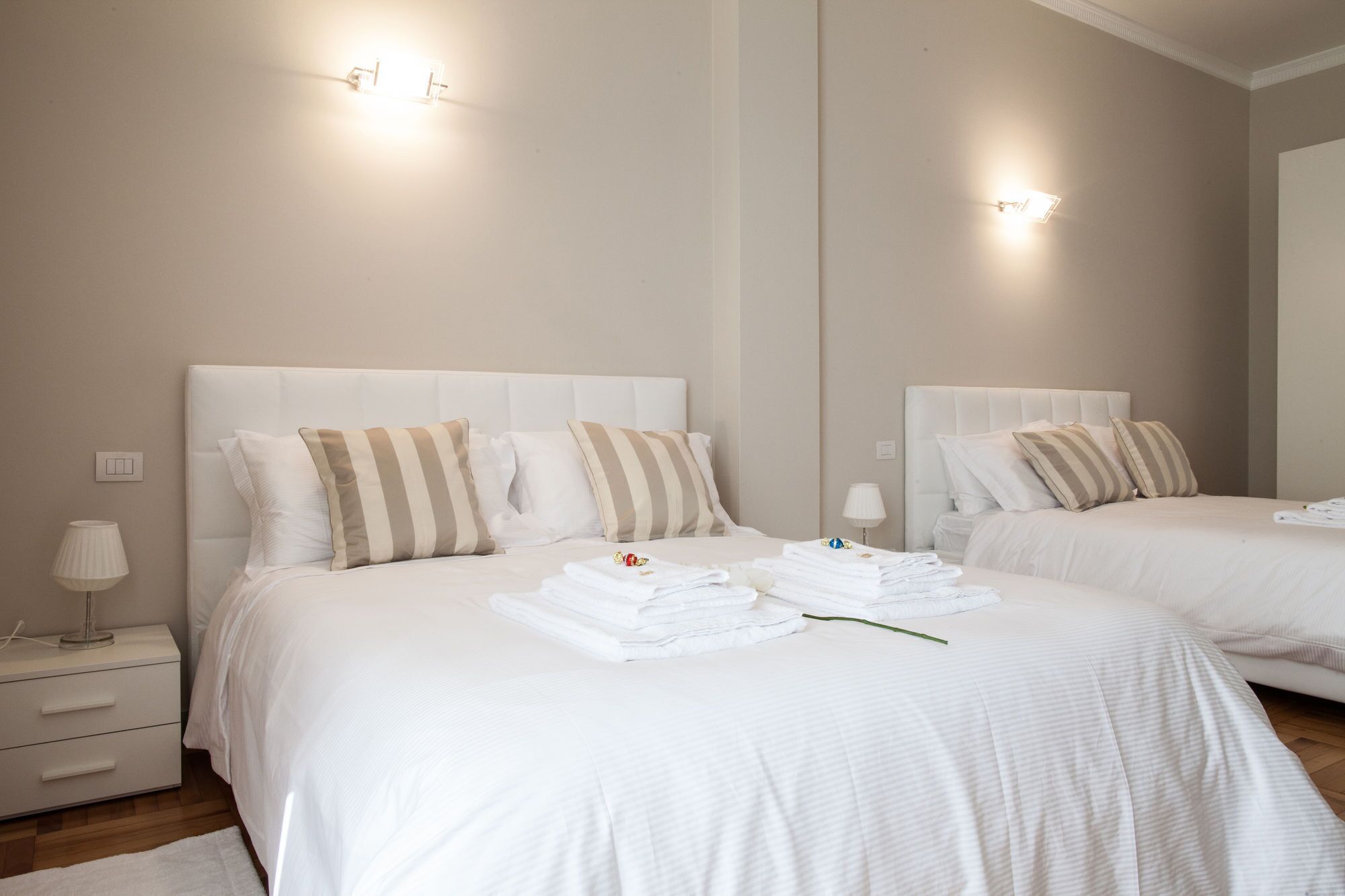Une chambre d’hôtel avec deux lits, chacun agrémenté d’oreillers à rayures, une table de chevet avec une lampe et un miroir au mur.