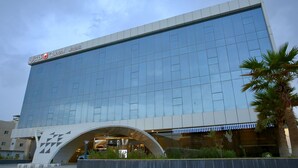 A modern hotel with a reflective glass facade, a prominent entrance with a curved overhang, and a visible sign indicating the hotel name. - Quetzal (Riyadh)