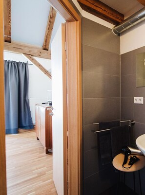 Ein modernes Badezimmer mit dunklen Fliesen, einem runden Waschbecken und einem Handtuchhalter.