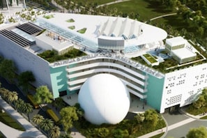 A modern hotel with a unique circular central structure, multiple floors, and surrounding greenery.