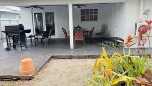 Un espacio al aire libre techado con una parrilla, sillas y una mesa.