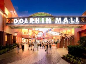 Entrada do Dolphin Mall com uma placa grande, uma cobertura e uma escada que leva ao nível superior.