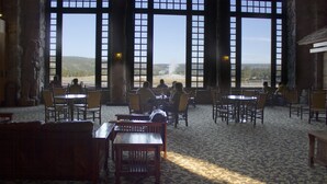 Comedor con ventanas amplias, mobiliario de madera y pared de piedra.