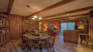A rustic wooden interior with a dining area, a living room, and a kitchen. - Perfect location, creekside, close to skiing, easy paved access, Game Pavilion! (Maggie Valley)