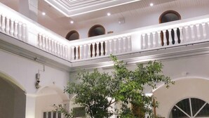 A multi-level atrium with a central tree, white railings, and arched doorways. - Xiamen·Lange Courtyard Garden Villa Guesthouse (Zhongshan Road Pedestrian Street Branch) (XIAMEN)