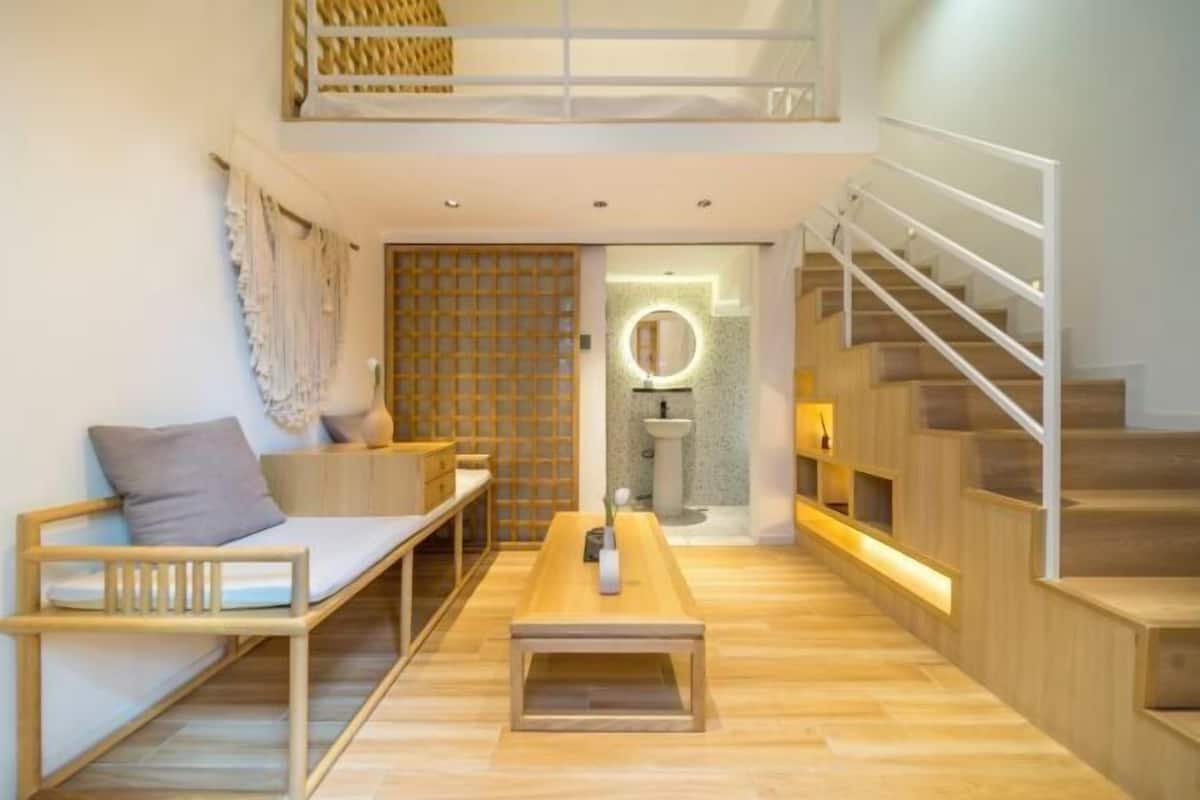A modern, open-plan living space with a wooden bench, a small table, and a staircase.