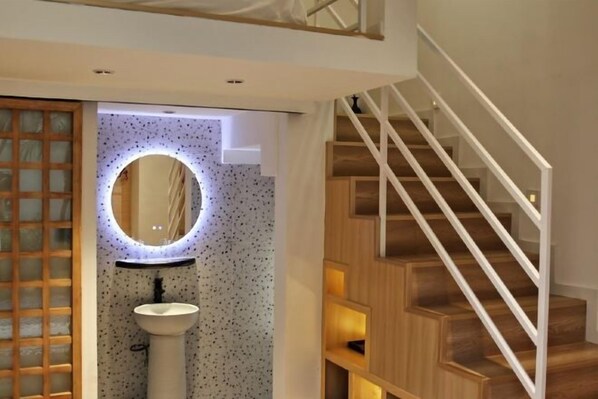 A modern bathroom with a freestanding sink, a round mirror, and a wooden staircase. - Xiamen·Lange Courtyard Garden Villa Guesthouse (Zhongshan Road Pedestrian Street Branch) (XIAMEN)