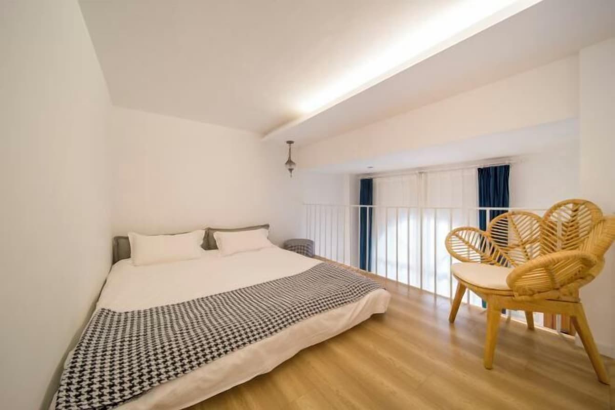 Un dormitori amb un llit, una cadira i una finestra amb cortines.