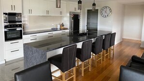 A modern kitchen with white cabinets, a black countertop, and a central island with bar stools.