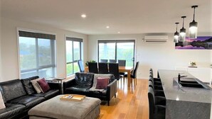 A modern living room with a sofa, ottoman, and dining area.