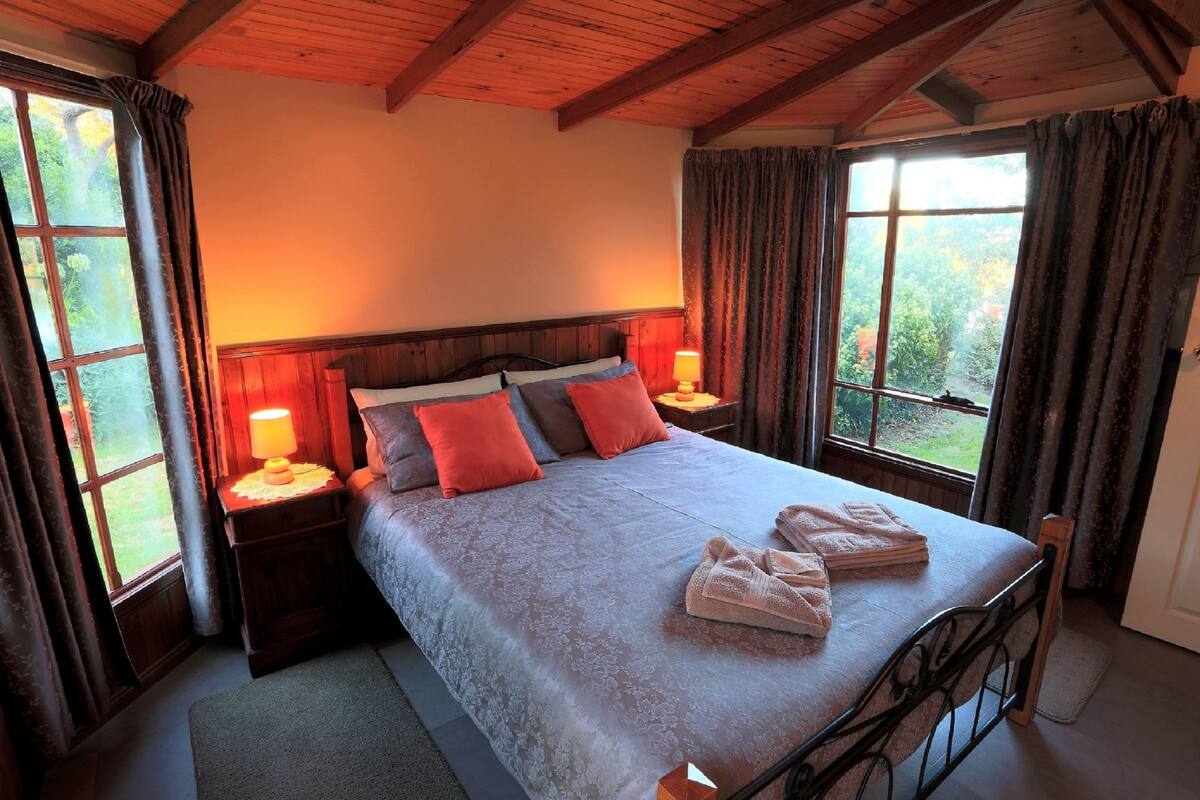 Ein Schlafzimmer mit einem großen Bett, zwei Nachttischen, einem Fenster mit Vorhängen.