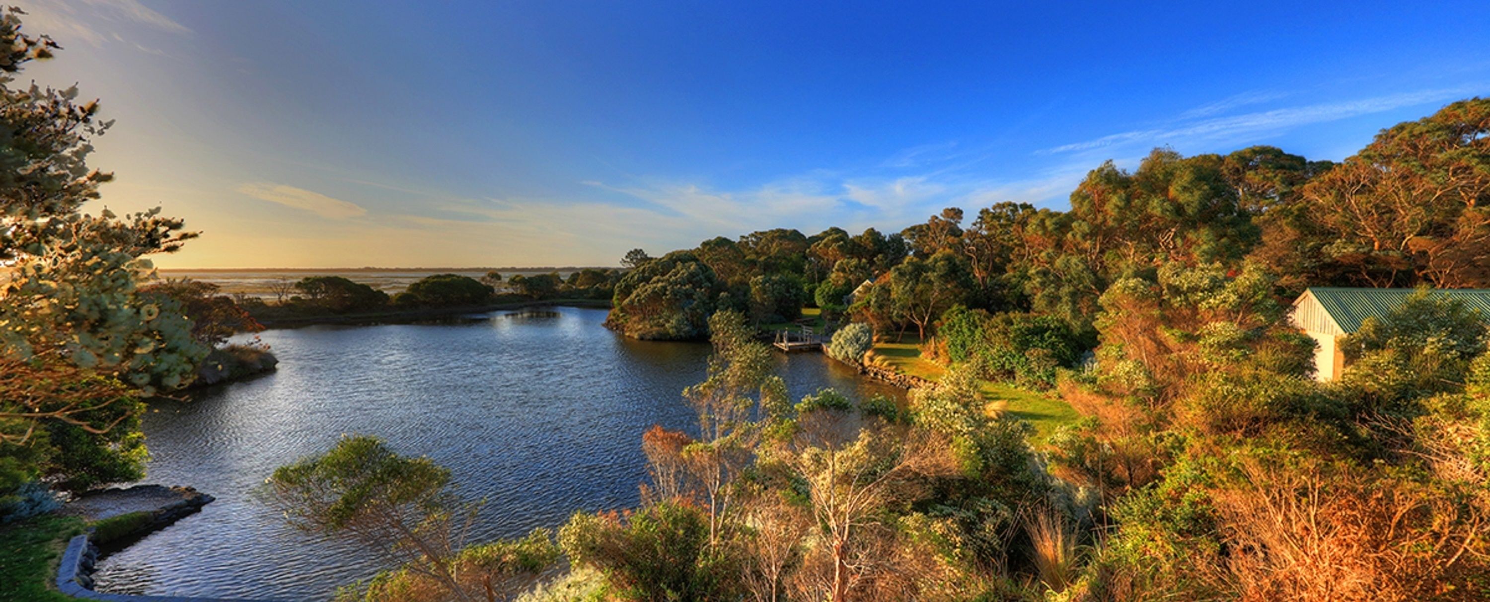 Una vista tranquilla su un lago, con vegetazione rigogliosa e un piccolo edificio con tetto verde.