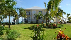 Un hôtel à plusieurs étages, doté d’un toit plat et entouré de palmiers et de plantes tropicales.