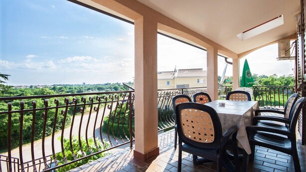 A balcony with a table and chairs, overlooking a green landscape and buildings. - A family apartment close to the beach - Dara 4 (Monterol)