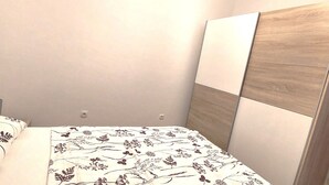 A bedroom with a bed, a wooden headboard, and a plain wall. - A family apartment close to the beach - Dara 4 (Monterol)